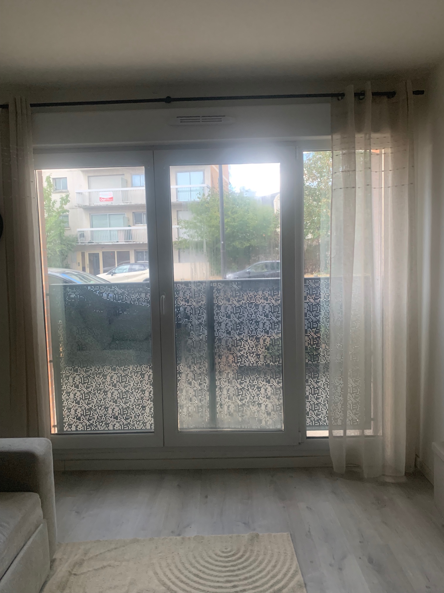 Salon lumineux avec porte-fenêtre équipée d'un film sans tain Maison KOVEL, rideaux ouverts en journée